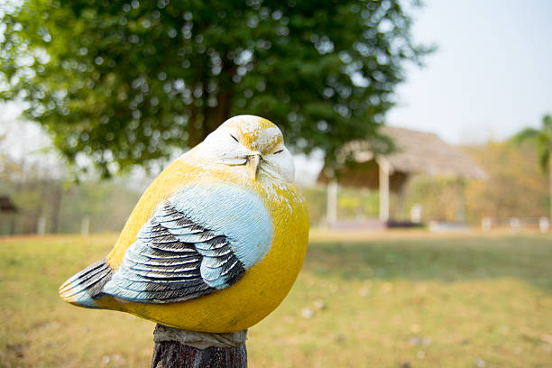 Hand carved woodpecker bird figurine displayed on a yellow wooden wall