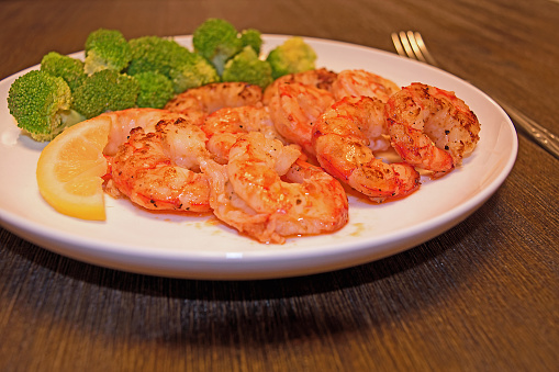 Cooked metapenaeus shrimp with lemon and broccoli on a wooden table