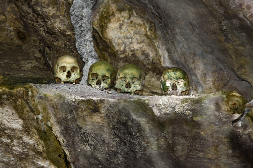 Skulls and cigarettes in Tampang Allo burial cave of the royal family. There are coffins are placed in caves or hanging from the cliff and wooden statues tau-tau guard the graves. Tana Toraja. South Sulawesi. Indonesia