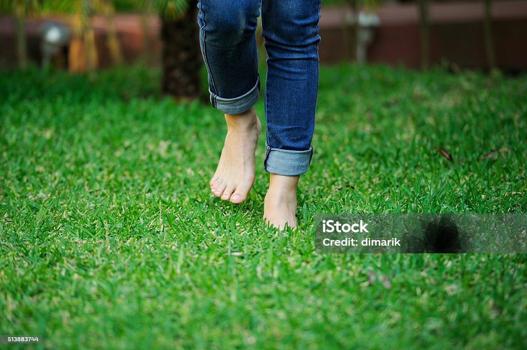 bare foot walking in grass bare foot preson in jeans walking in green grass Barefoot Stock Photo