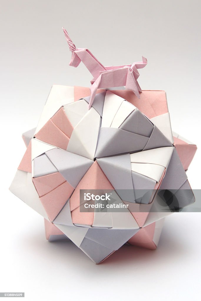 Origami unicorn riding paper ball Pink origami unicorn riding colorful origami ball isolated on white Abstract Stock Photo