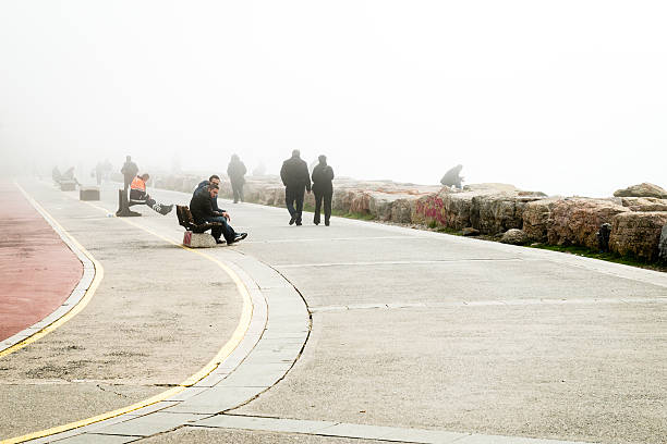 Istanbul, Turkey - February 29, 2016: People are spending time on the coast in Kadikoy. Deep fog is covering Istanbul