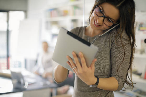 Beautiful confident woman on the phone while using digital tablet