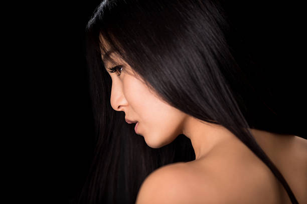 Close-up profile of young asian lady demonstrating black hair. Back view of beautiful woman looking away and showing her gorgeous hair in studio.
