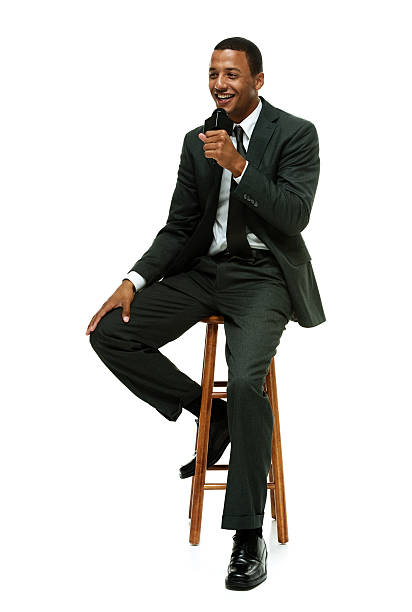 istock Smiling businessman on stool & holding microphone 513904899