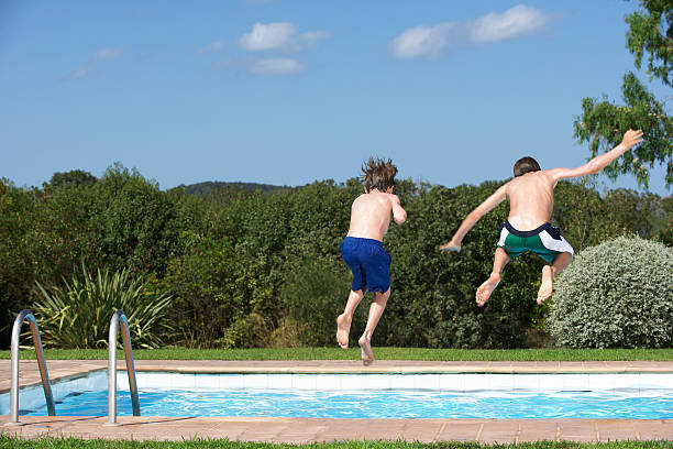 istock Rear View Of Boys Jumping Into Pool 513916801
