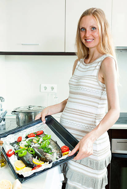 istock Woman cooking trout fish in pan 513918385