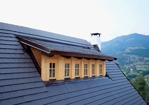 Attic dormers and chimneys on a rooftop with mountain background, Reconstruction of roof