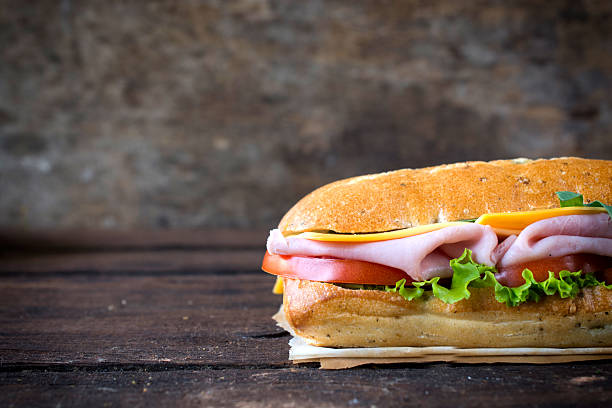 Sandwich Tasty panini sandwich stuffed with ham and vegetables on wooden background with blank space on left side,selective focus submarine sandwich photos stock pictures, royalty-free photos & images