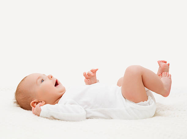 Baby in White Onesie Lying on Back, Toddler Kid Bodysuit Baby in White Onesie Lying Down on Back, Happy Toddler Kid in Bodysuit Looking Up lying on back stock pictures, royalty-free photos & images