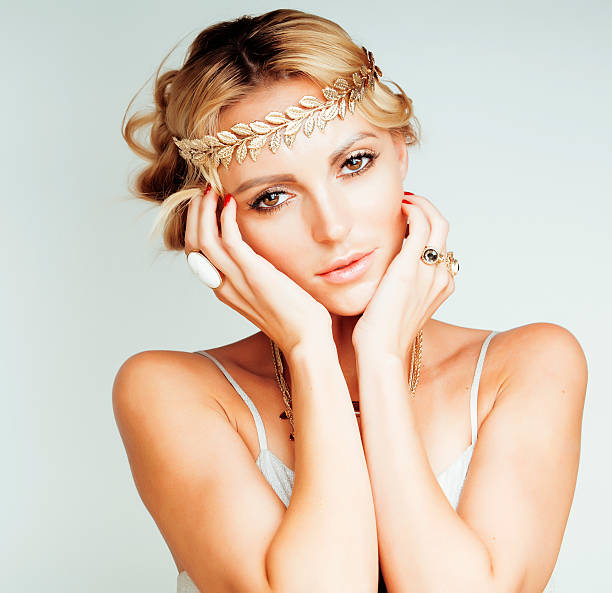 young blond woman dressed like ancient greek godess, gold jewelry stock photo