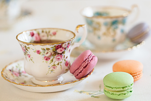 Two cups filled with tea and some macaroons