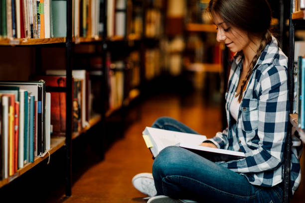 istock Woman in the library reading book. 513942136