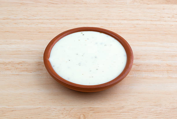 Bowl of ranch dressing on a wood table top Side view of a small bowl of ranch dressing on a wood table top illuminated with natural light. ranch dressing stock pictures, royalty-free photos & images