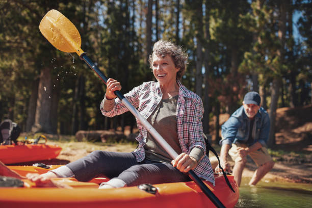 matura coppia godendo una giornata sul lago con il kayak - retirement living foto e immagini stock