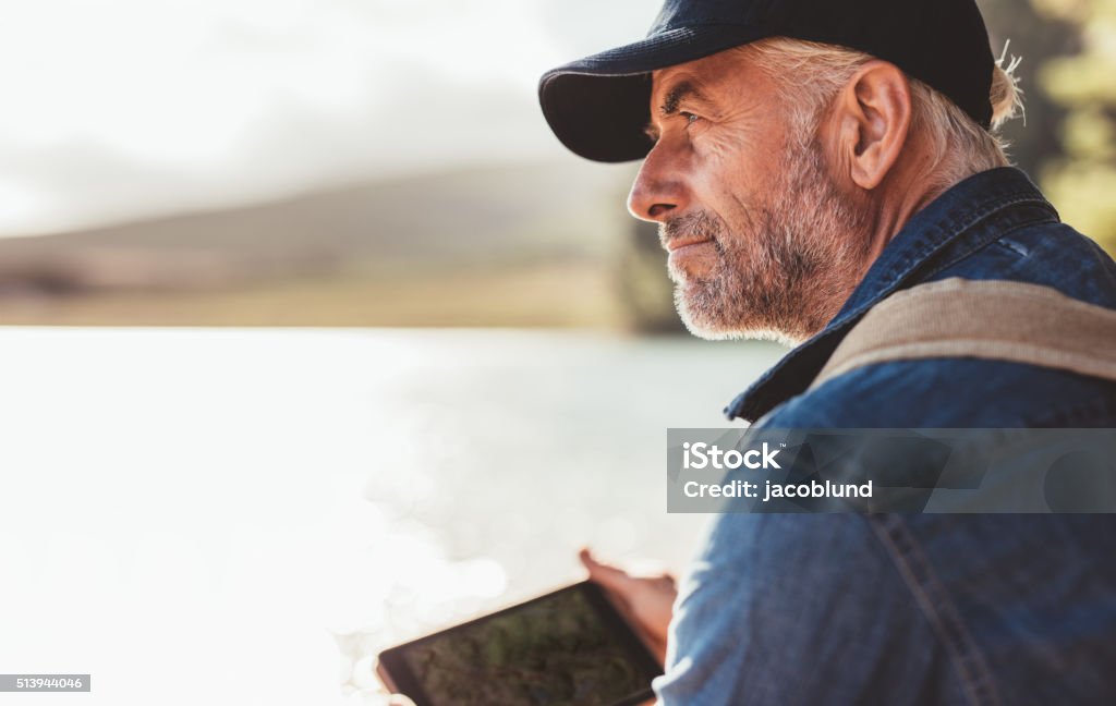 Mature man wearing cap sitting at a lake Close up portrait of mature man wearing cap sitting at a lake and looking at a view. Senior caucasian man with beard. Men Stock Photo