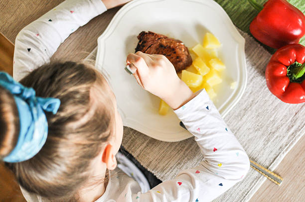 Tuna steak and potatoes, great meal for children Young girl eating grilled tuna steak and boiled potatoes, Indoors shot of a little girl having a healthy meal decorated with red paprika. kids eating tuna stock pictures, royalty-free photos & images