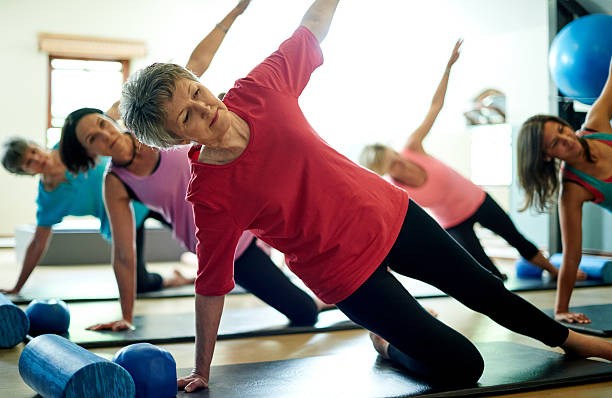 Staying supple in her senior years with pilates Shot of a group of women doing the side plank workout in a pilates classhttp://195.154.178.81/DATA/i_collage/pu/shoots/806460.jpg pilates photos stock pictures, royalty-free photos & images