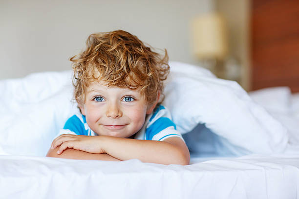 istock Adorable kid boy after sleeping in his white bed 513948586