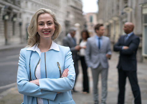 Successful business woman on the street with a group of workmates at the background