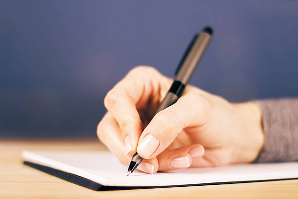 istock Girl writes notes in diary on wooden table, close up 513951172