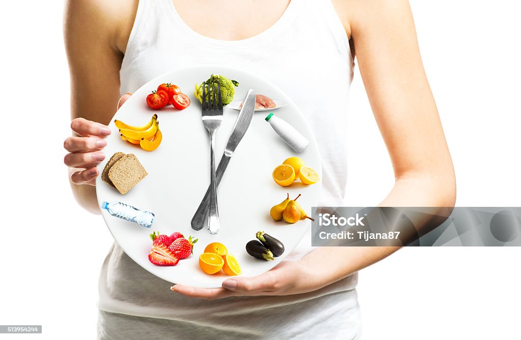 Beautiful young woman holding a plate with food Beautiful young woman holding a plate with food, diet and time concept close up  Healthy Eating Stock Photo