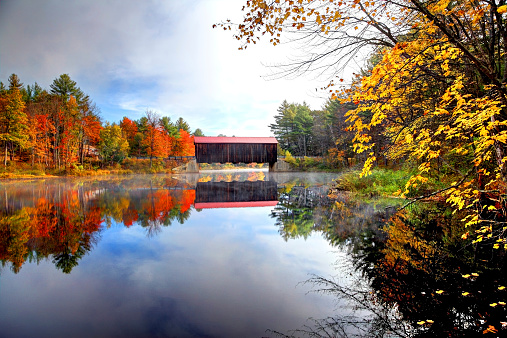 Autumn colors surround the County Covered Bridge in rural New Hampshire. Photo taken during peak fall foliage season along the Contoocook River near Greenfield. New Hampshire is one of New England's most popular fall foliage destinations bringing out some of  the best foliage in the United States