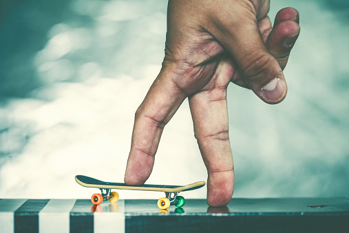 Close up of a hand playing with a mini-skateboard