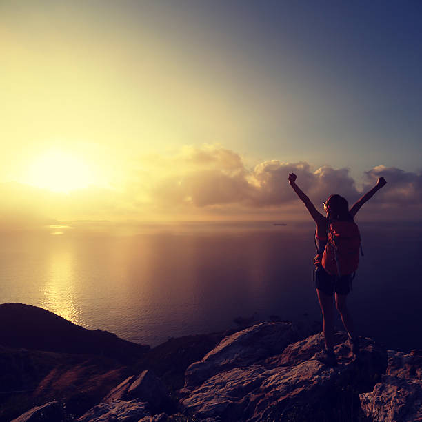 istock cheering young woman backpacker at sunrise seaside mountain peak 513985196