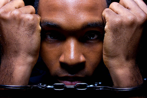 Close Up of a Black Man in Hand Cuffs close up portrait of hand cuffed black man criminal activity stock pictures, royalty-free photos & images