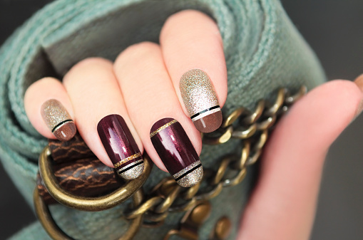 Golden brown French manicure with black stripes on the background of the accessory.