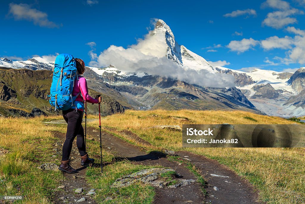 Sporty hiker woman with Matterhorn peak in background,Valais,Switzerland Hiker woman with backpack and mountain equipment,looking at view in Valais region,Matterhorn,Switzerland,Europe Zermatt Stock Photo