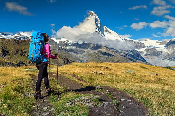 Hiker woman with backpack and mountain equipment,looking at view in Valais region,Matterhorn,Switzerland,Europe