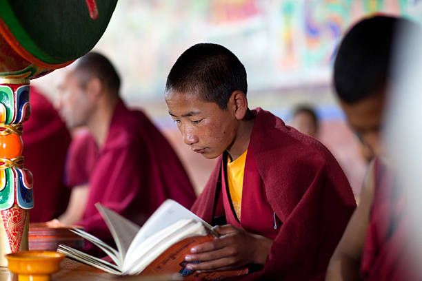 Ladakh, India - June 11, 2012: Young Tibetan Buddhist novice monk praying in Thiksey gompa (Buddhist monastery) of the Yellow Hat (Gelugpa sect).