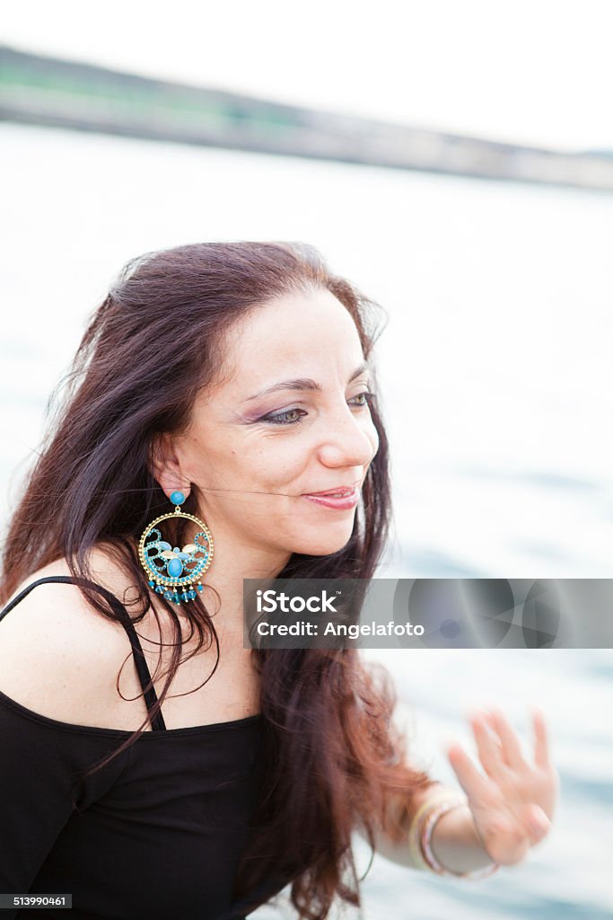 Beautiful Woman on Pier, Cloudy Sky Beautiful brunette woman with blue eyes on pier during a cloudy day. Adult Stock Photo