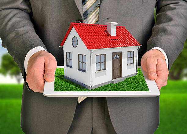 istock Hands hold tablet pc. Small house with red roof on 513990741