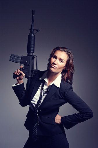 A young businesswoman wearing a suit and tie holding a rifle