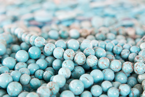 shallow depth of field on assorted strings of turquoise beads fill the frame and fading into the background