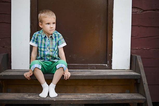 istock Smiling young blond boy sitting on porch steps at home 513999528