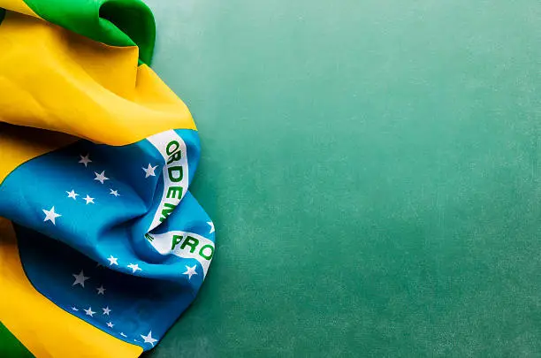 A Brazil flag is laying on a green chalkboard background