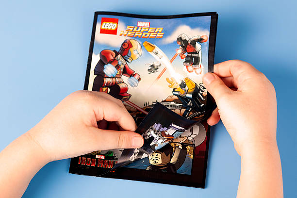 Childs hands open comic book Lego Marvel Super Heroes Tambov, Russian Federation - January 12, 2015: Childs hands open comic book Lego Marvel Super Heroes. Blue background. Studio shot. reading comic book stock pictures, royalty-free photos & images