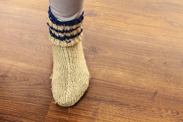 istock Woman foot wearing woolen warm sock on floor 514005412