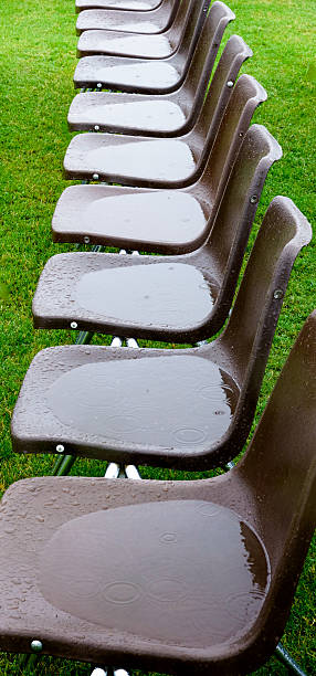 istock Rained Out - row empty rain-soaked event chairs, wet grass 514026469