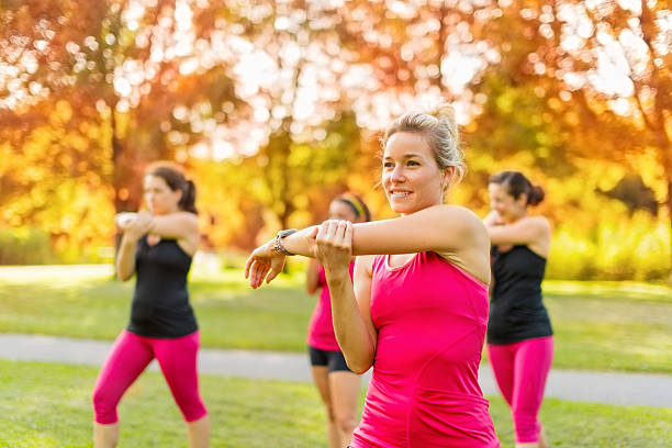 Portrait of a smiling young woman streching her arm before jogging with friends