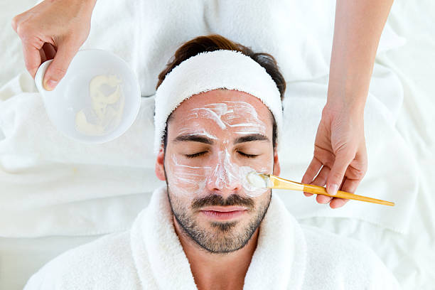 uomo con maschera viso argilla nel salone di bellezza. - massaging spa treatment health spa men foto e immagini stock