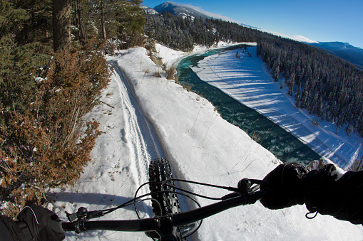 The handlebar view during a winter fat bike ride on a singletrack trail in British Columbia, Canada.