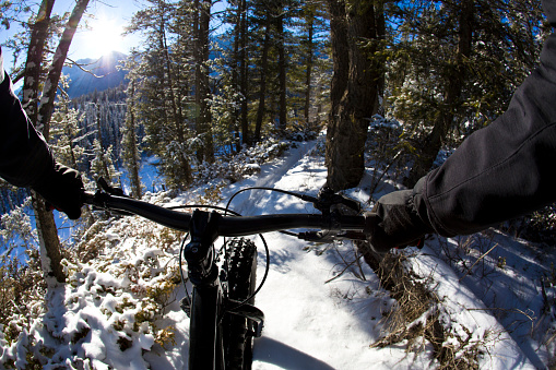 The handlebar view during a winter fat bike ride on a singletrack trail in British Columbia, Canada.