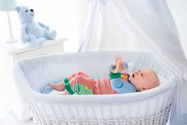 istock Sweet little baby with bottle in white bed 514054208