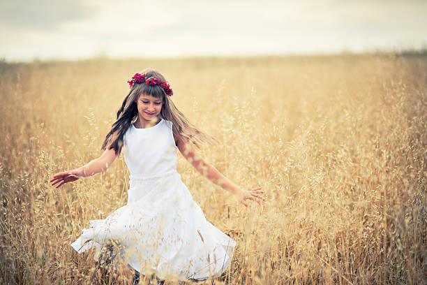 Beautiful young brunette woman in a white dress is enjoying spring in a field of daisies. Health idea and concept, beautiful healthy hair and skin, lack of allergies