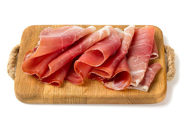 sliced prosciutto on a wooden board sliced prosciutto on a wooden board isolated on white background parma ham stock pictures, royalty-free photos & images